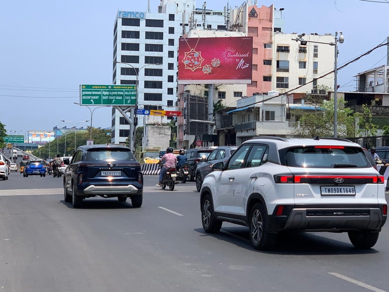 Urban street scene with multiple vehicles on a busy road, tall apartment buildings, and advertising billboards in the background