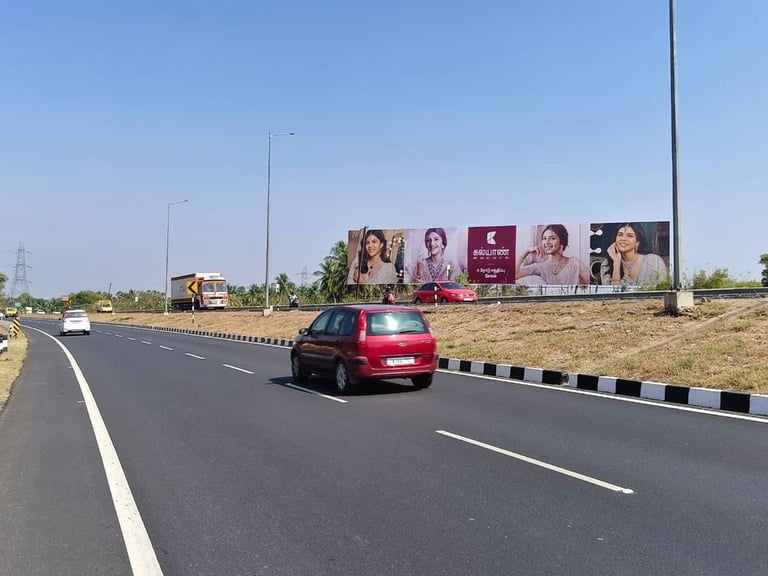 Red car driving on highway with large billboards visible on the roadside under clear blue sky