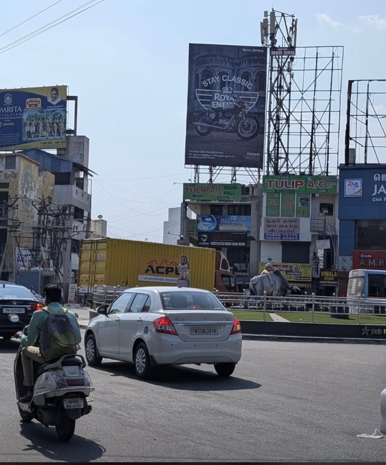 Urban street scene with white sedan car, motorcyclist, and buildings with billboards and signage