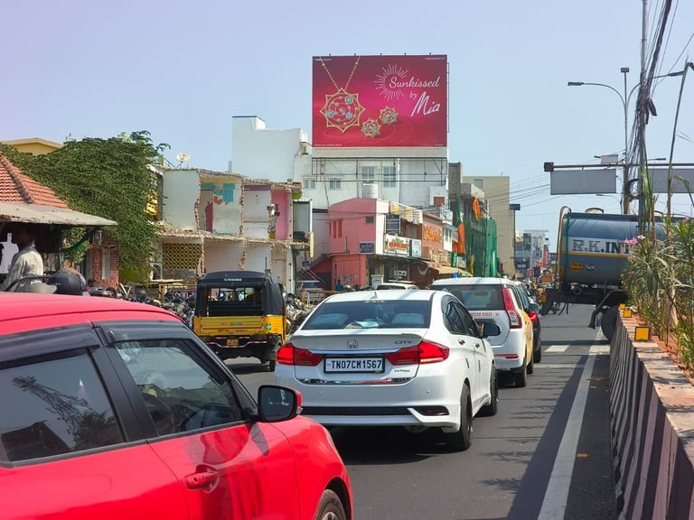Busy urban street with traffic jam, colorful buildings, and red billboard in an Indian city