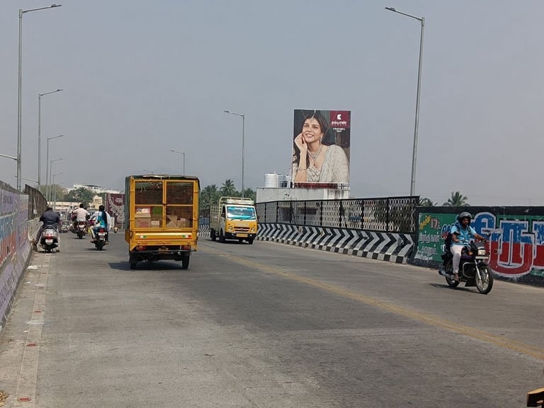 Street scene with yellow truck, motorcycles, and large billboard on overpass during daytime