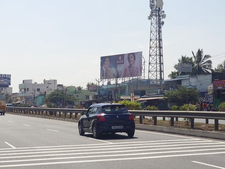 Dark car driving on a highway with a tall telecommunications tower and large billboard visible in the urban background