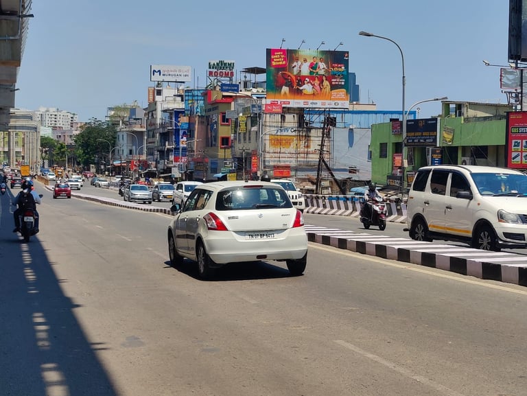 Busy urban street in India with traffic, white vehicles, colorful buildings and billboards