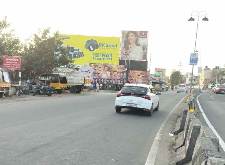 Urban street scene with white car driving past large billboards and commercial trucks on a busy road