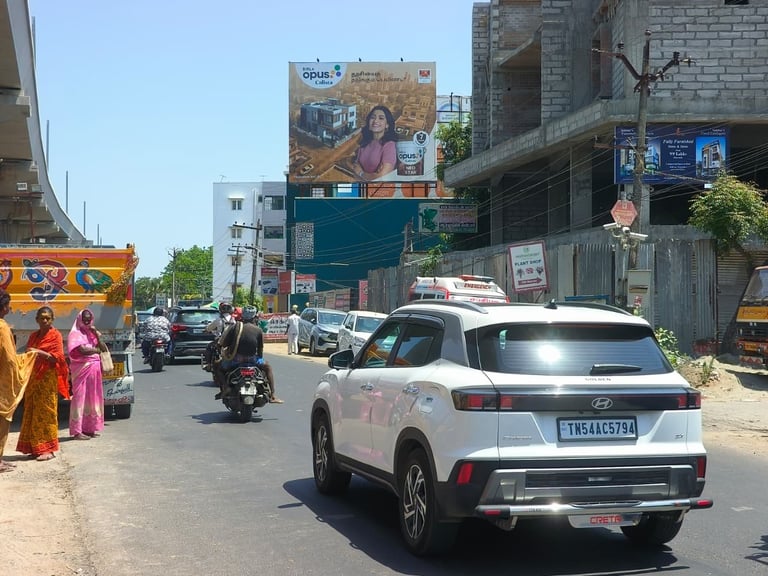 White SUV on a busy Indian street with motorcycles, colorful buildings, and billboards